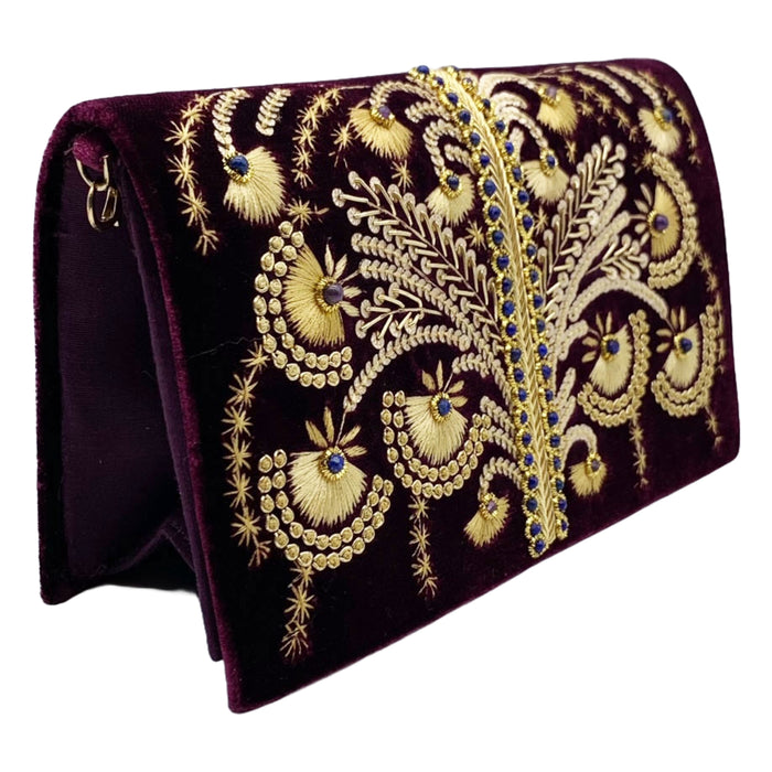 A purple velvet clutch with gold beadwork and embroidery, featuring a removable gold-toned chain shoulder strap.
