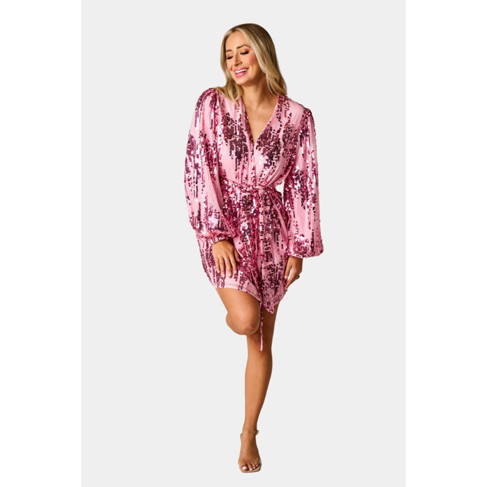 Model wearing a loose fit wrap with tied waist, and mid-thigh length in pink sequined fabric