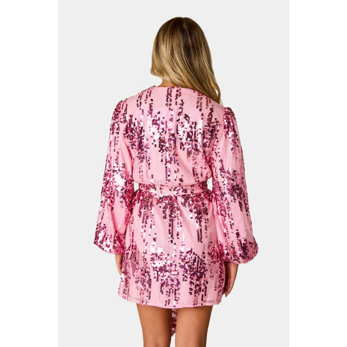 Model wearing a loose fit wrap with tied waist, and mid-thigh length in pink sequined fabric