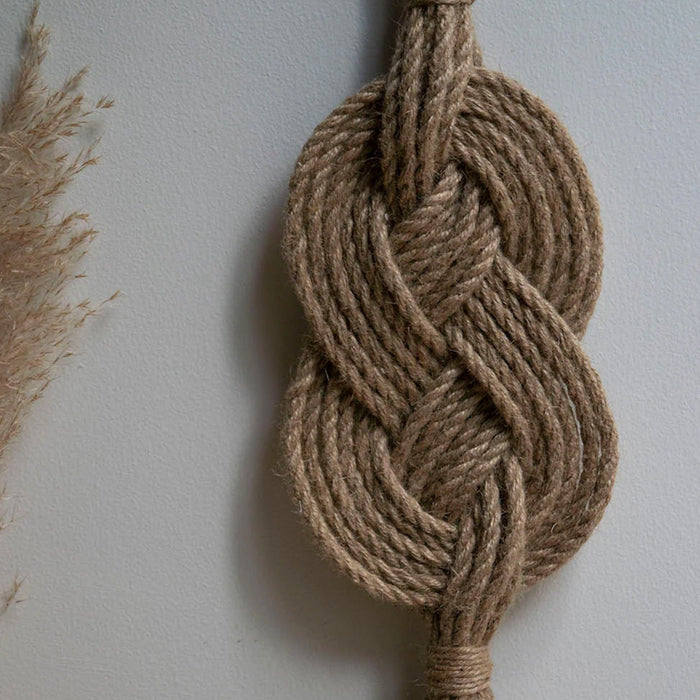A handmade wall hanging decoration made with natural jute fiber rope, featuring a braided geometric pattern.