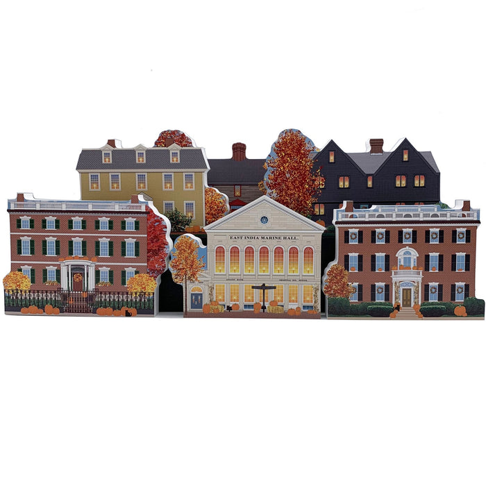 A collection of handcrafted wooden models of historic houses, decorated with autumn-themed elements such as pumpkins and fall foliage.