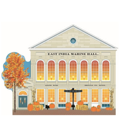 A handcrafted wooden model of the historic East India Marine Hall, decorated with autumn-themed elements such as pumpkins and fall foliage.
