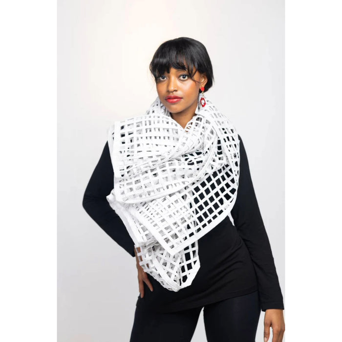 A person wearing a white grid sewn scarf wrapped around the neck, paired with a dark top.