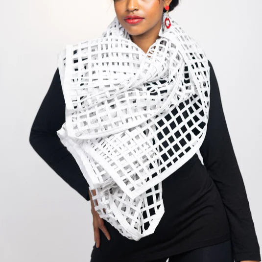 A person wearing a white grid sewn scarf wrapped around the neck, paired with a dark top.