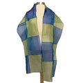 A scarf wrap displayed on a mannequin bust, featuring a grid work pattern in royal blue and lime green squares.