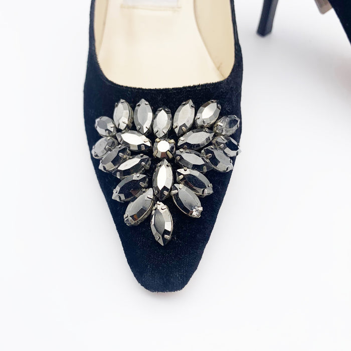 A pair of black velvet high-heeled shoes with dark grey rhinestone embellishments on the front, designed by Emma Hope.