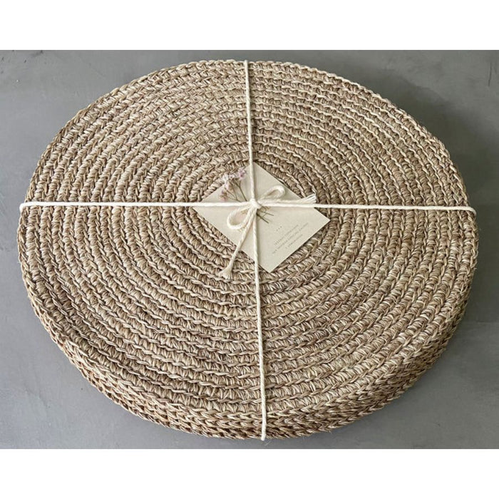 Four round handwoven, natural fibre placemats made by Colombian artisans in beige tones wrapped in a cotton twine